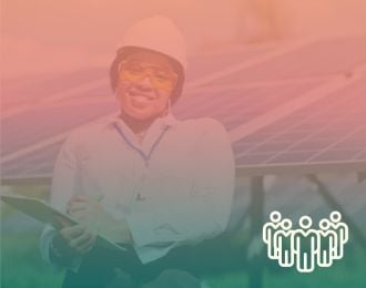 A female technician stands in front of solar panels