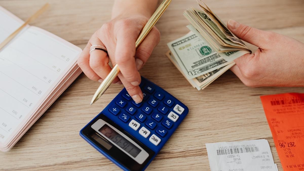 a person using a calculator and holding cash in their hand
